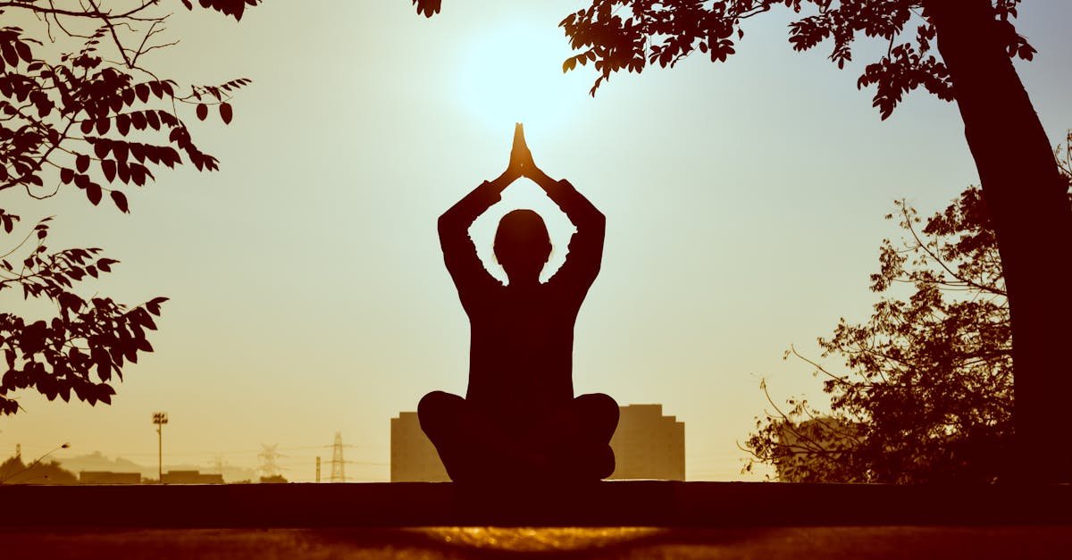 Silhouette of a person practicing yoga outdoors during sunrise, creating a calming atmosphere.