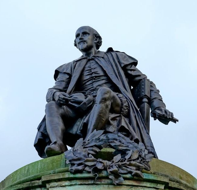 Statue of William Shakespeare in Stratford-upon-Avon, England against a cloudy sky.