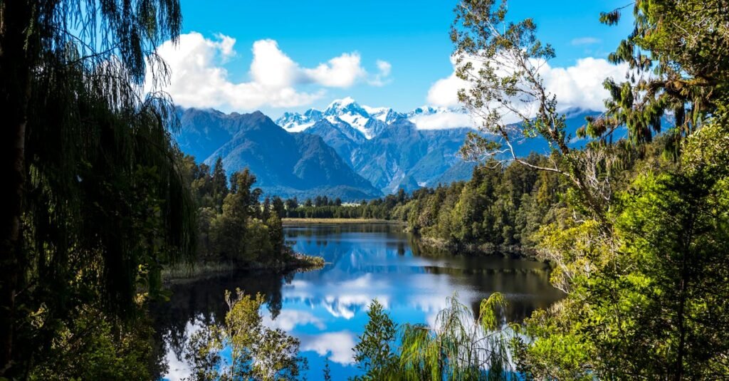 Stunning view of a clear lake surrounded by snow-capped mountains and lush forest.