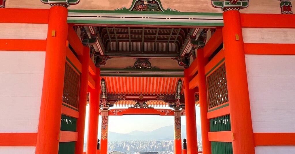 Colorful entrance of a Japanese temple under bright sunlight with mountainous background.