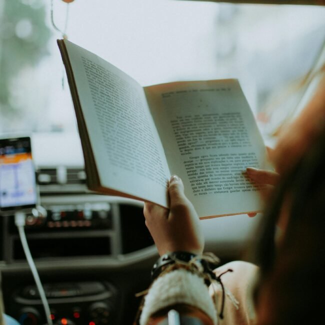 Person enjoying a book in a car, adding leisure to a road trip adventure.