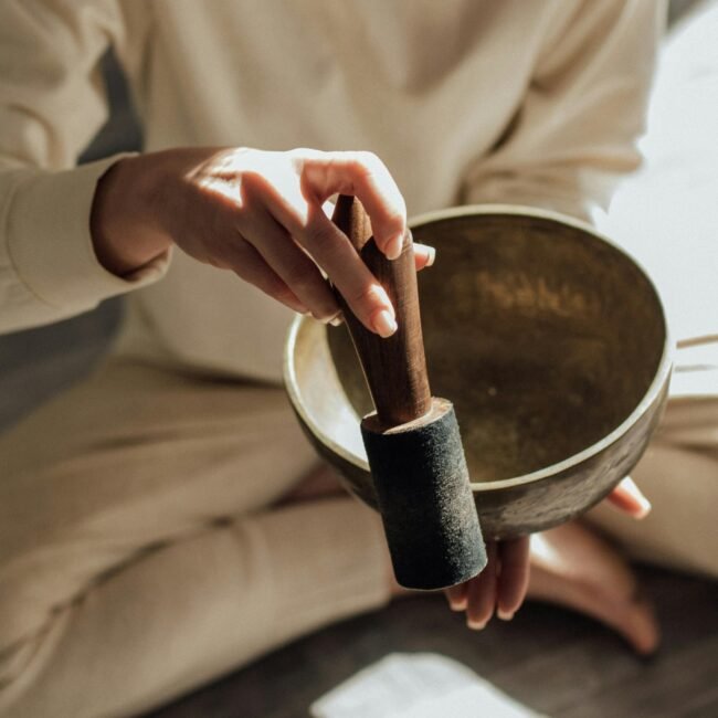 A person holds a Tibetan singing bowl with a mallet, symbolizing meditation and relaxation.